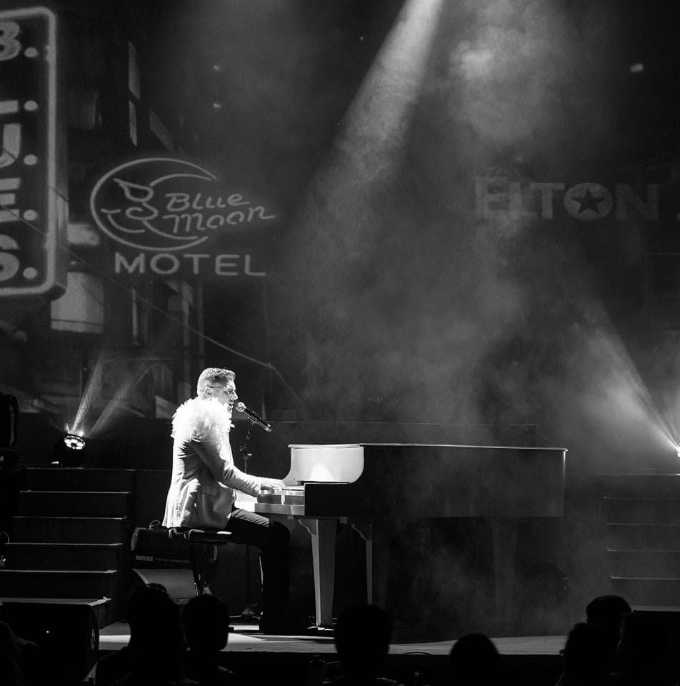 Evan at the white grand piano under stage smoke